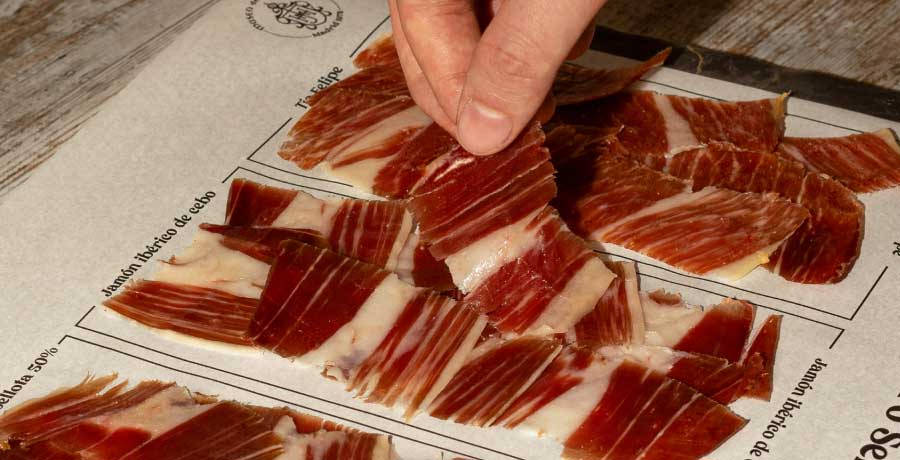 Selección de jamón ibérico dispuesta para degustación en un evento, con lonchas finas listas para ser disfrutadas.