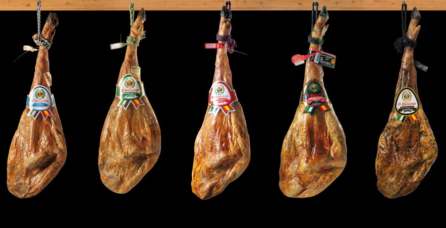 Diferentes tipos de jamón ibérico con etiquetas de clasificación según su calidad y alimentación.