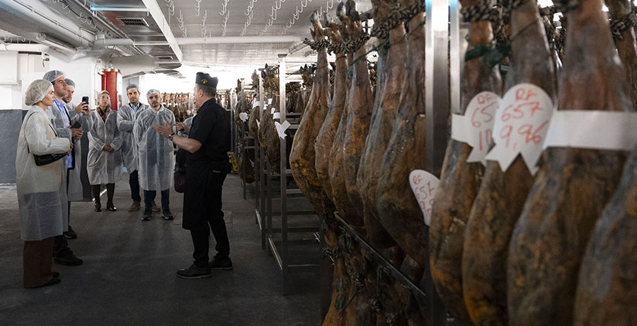 Grupo en un recorrido por una sala de curación de jamón ibérico, mostrando las etapas de su producción artesanal.