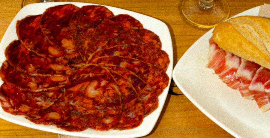 Chorizo ibérico de bellota cortado en lonchas junto a bocadillo