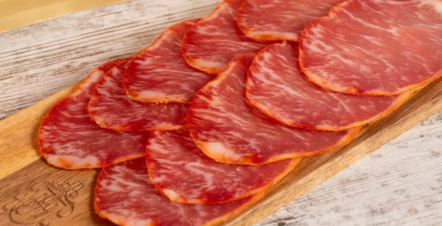 Lonchas de lomo ibérico sobre tabla de madera, embutido tradicional español