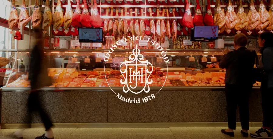 Mostrador del Museo del Jamón con jamones ibéricos y clientes comprando