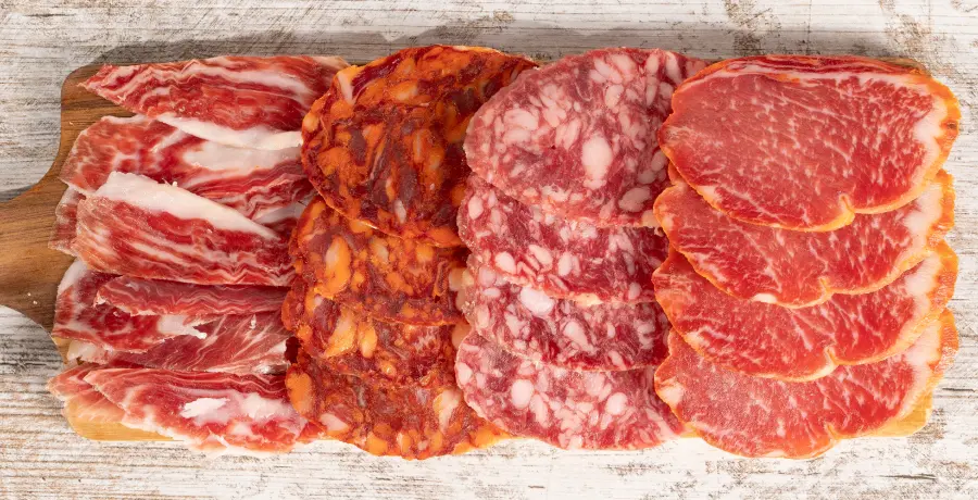 Tabla de embutidos ibéricos con jamón, chorizo, salchichón y lomo sobre madera